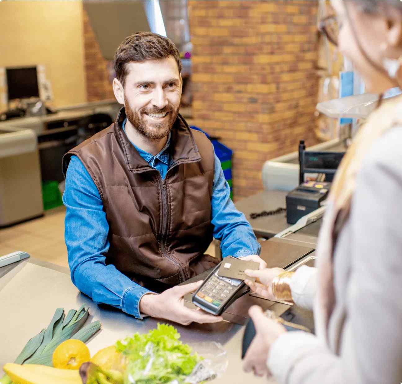 Retail Genie - A person hold payment machine, and a customer scan her credit card on this machine for payment